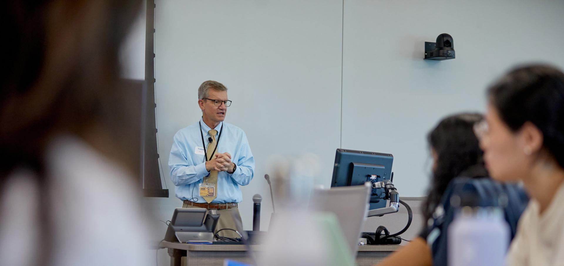 Instructor in white coat teaching students in the classroom