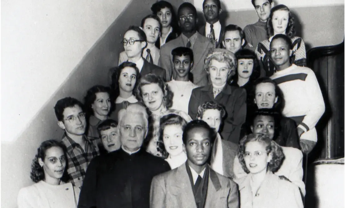 Fr. Markoe (front, second from left) stands by stairs in Creighton Hall with members of the Omaha DePorres Club in the 1940's (black and white photo)