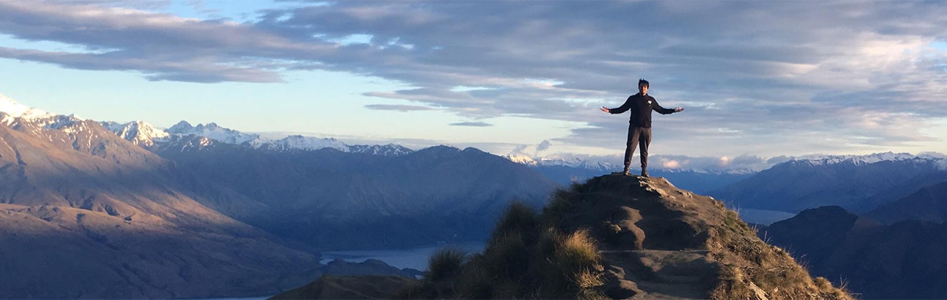 A student standing on top of a mountain peak in Australia