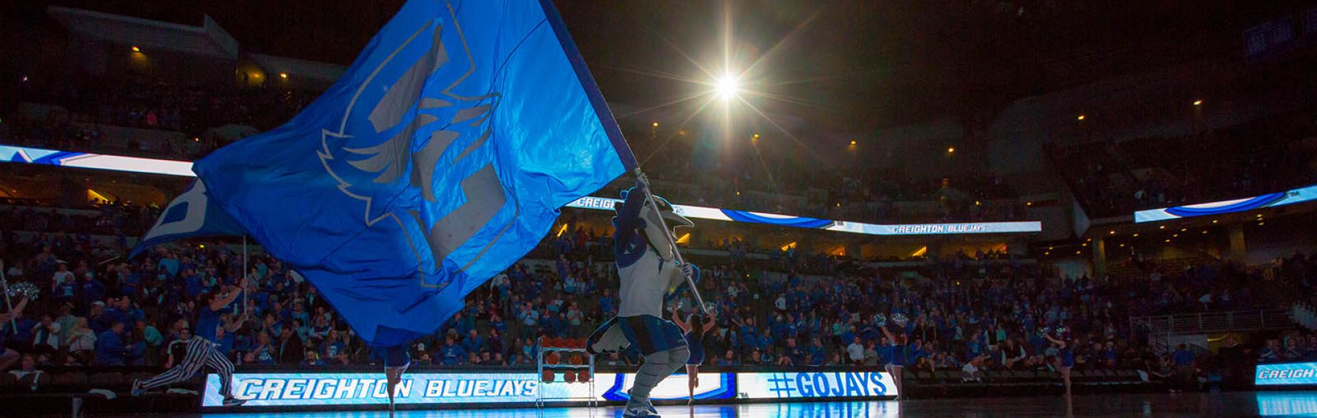 Billy Bluejay at Basketball Game with Flag
