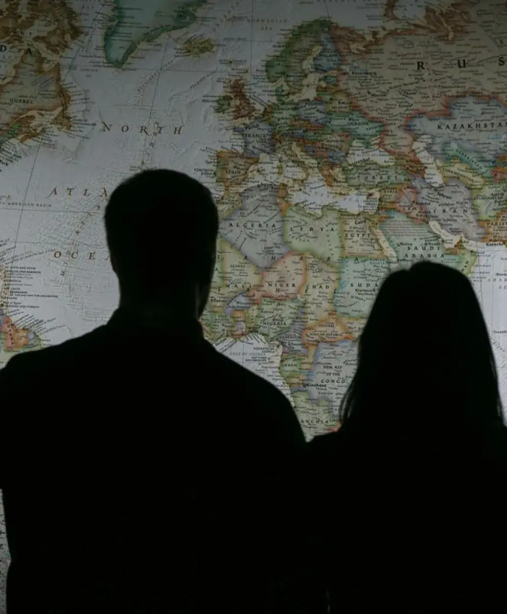 Woman and man silhouetted in front of world map