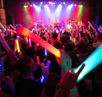 Students with glow sticks waving them in party atmosphere.