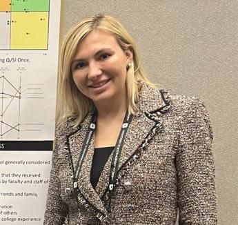 Anna Kotula smiling beside her research poster.