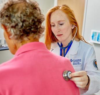 Morgan Hopp examining patient with stethoscope.
