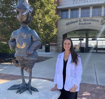 Jaclyn Taylor standing outside Morrison Stadium on Creighton campus next to Billy Bluejay statue.