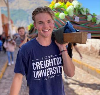 Ryan Berg smiling on procession with fellow students and wearing Creighton t-shirt.