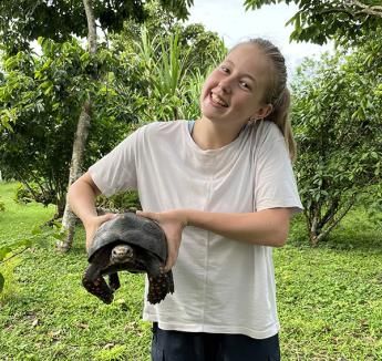 Emma Moran holding large turtle and smiling.