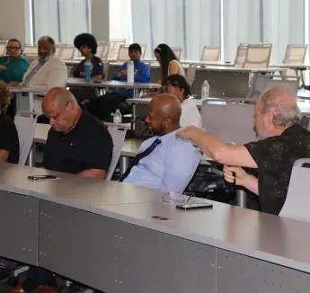 Community members participate in a health education workshop, with one attendee speaking into a microphone.