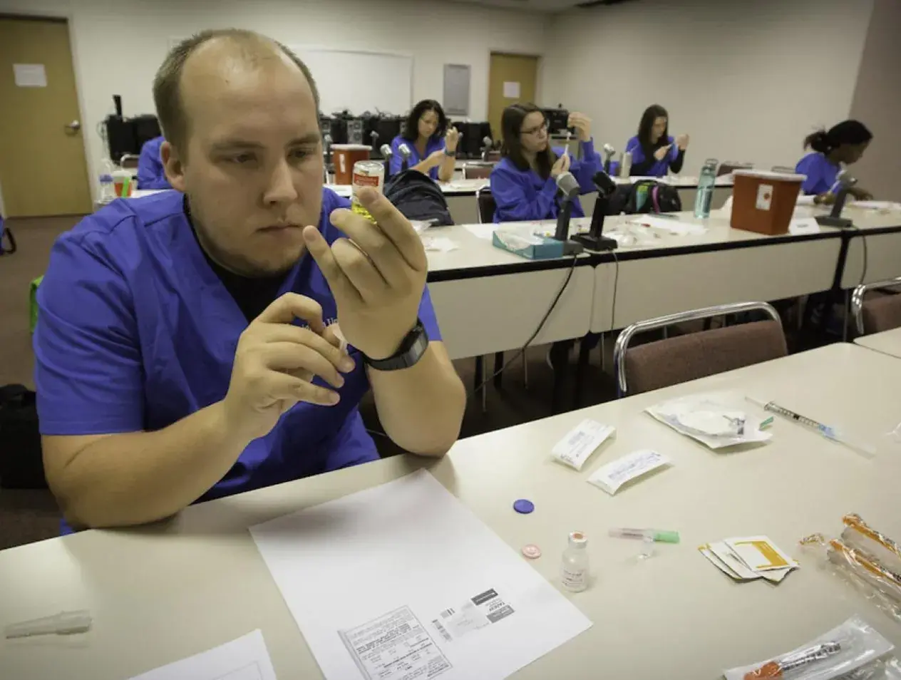 Students learning to use hypodermic needles