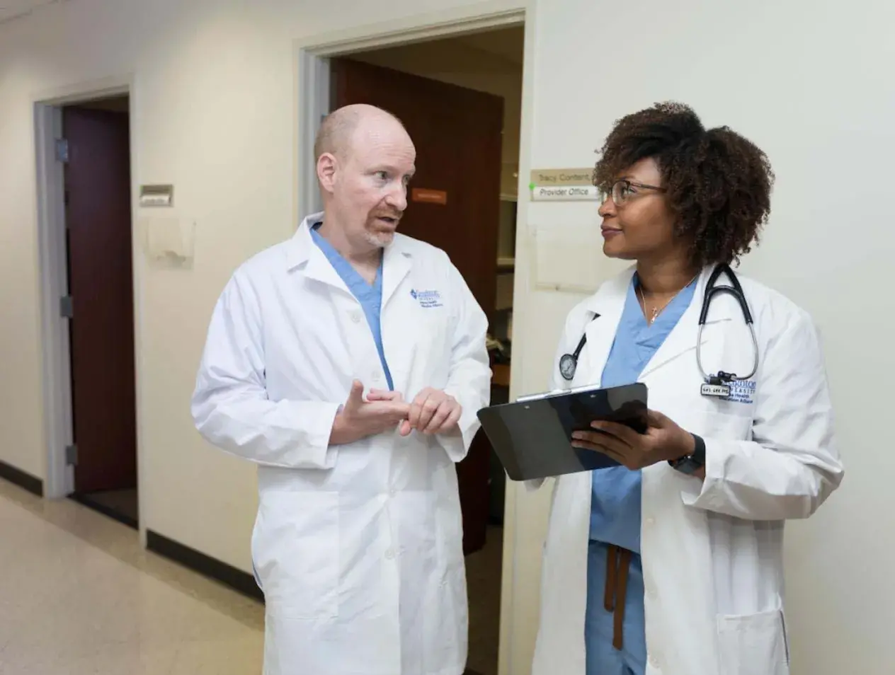 Dr. Brady talking to professional in hospital hallway.
