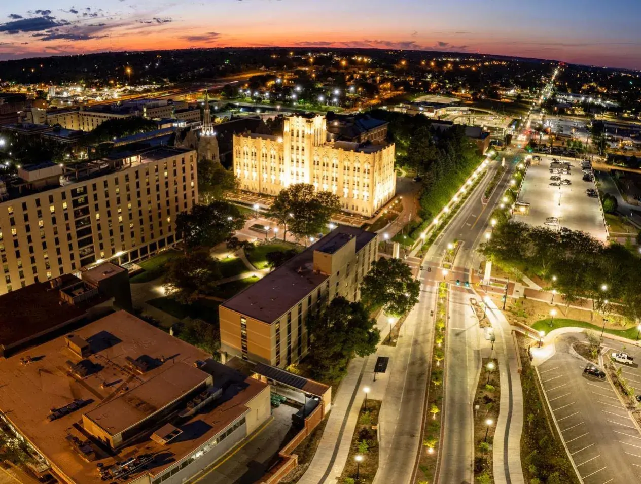 Horizon shot of Creighton campus with lights on as sun rises.