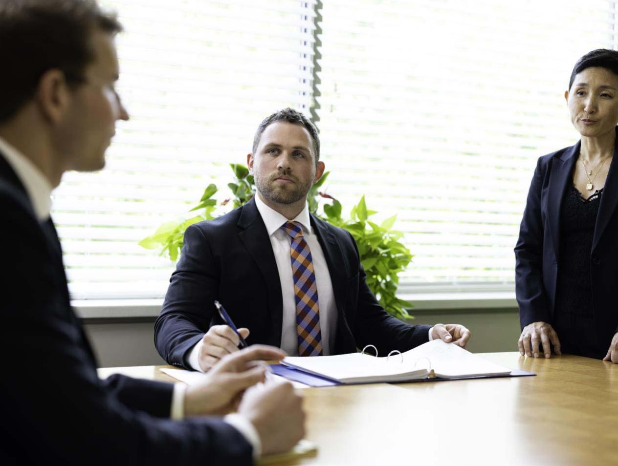 Three individuals talking in business clothes at conference table.