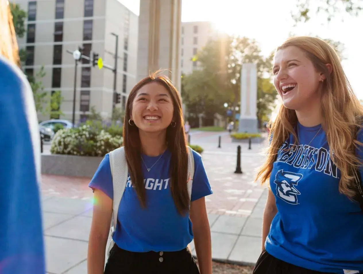 Female student talking in small group outside on campus mall on warm spring morning day.