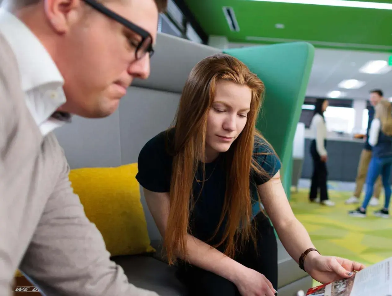 Two people looking over brochure in business setting.