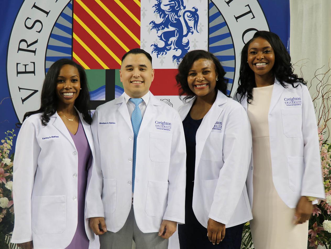 Students smiling in Creighton white coats.