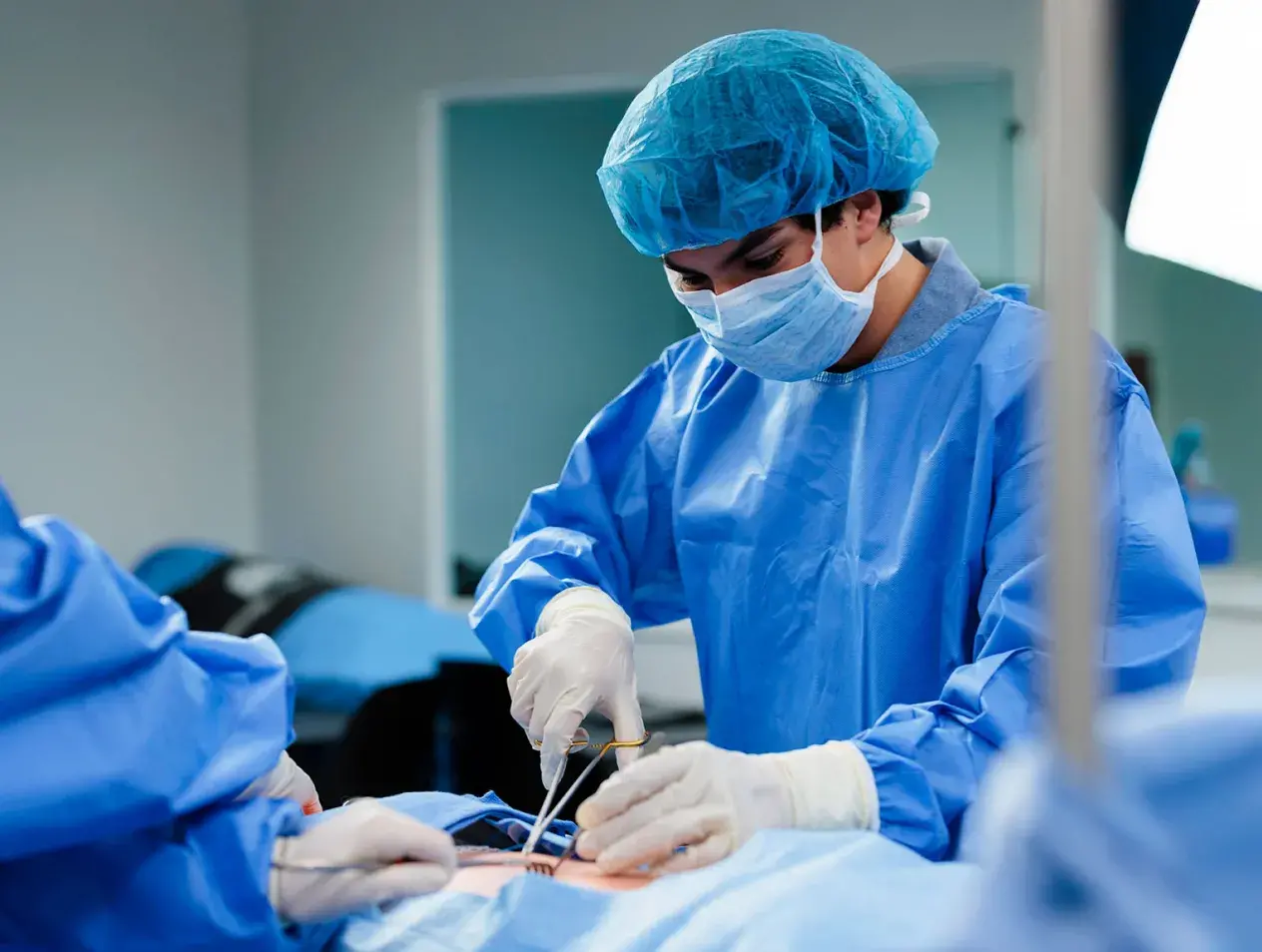 Student in blue scrubs performing a surgery procedure