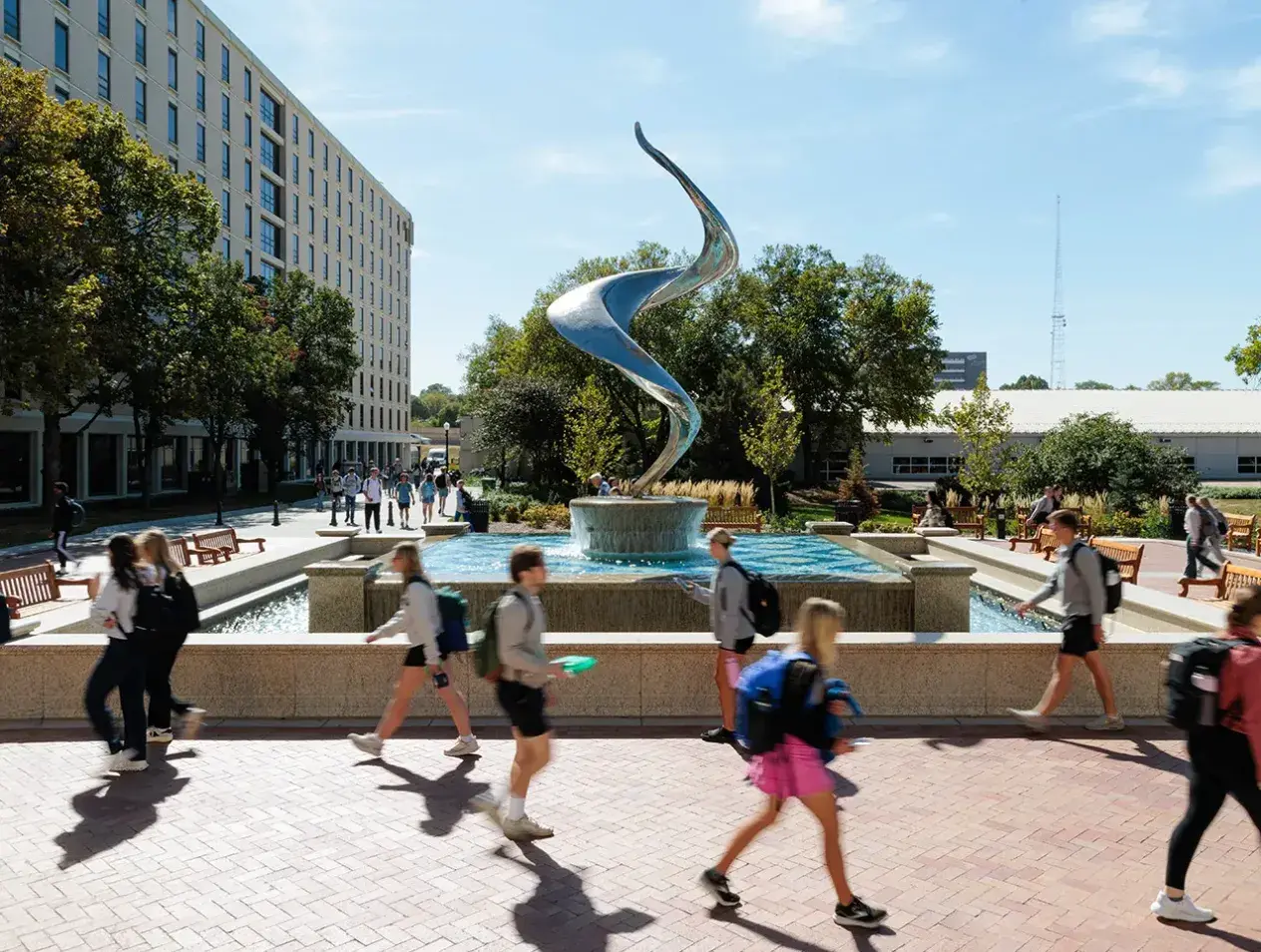 Students walking by flame fountain during summer.