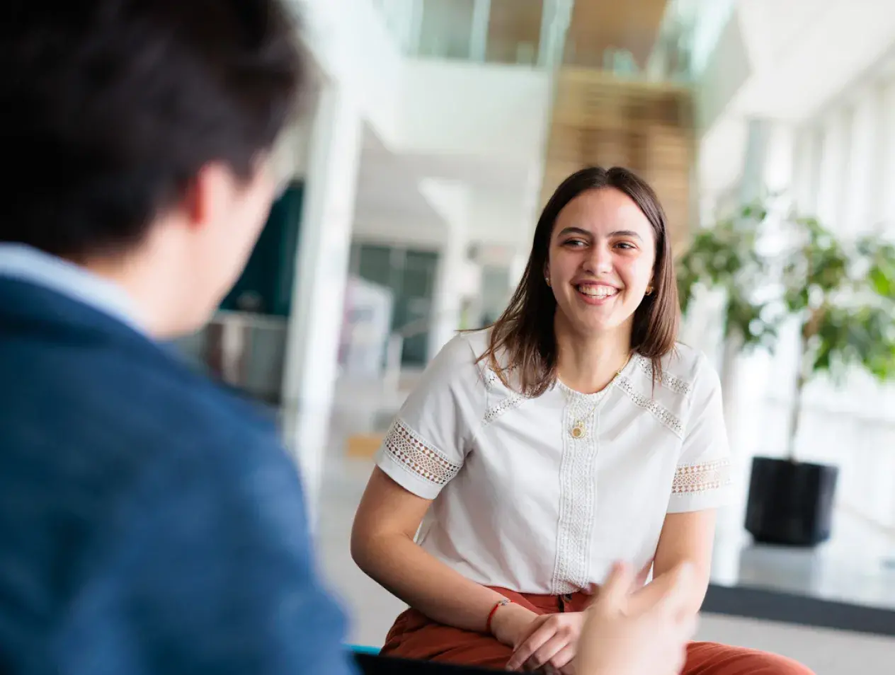 Female student sitting and smiling while talking with someone else