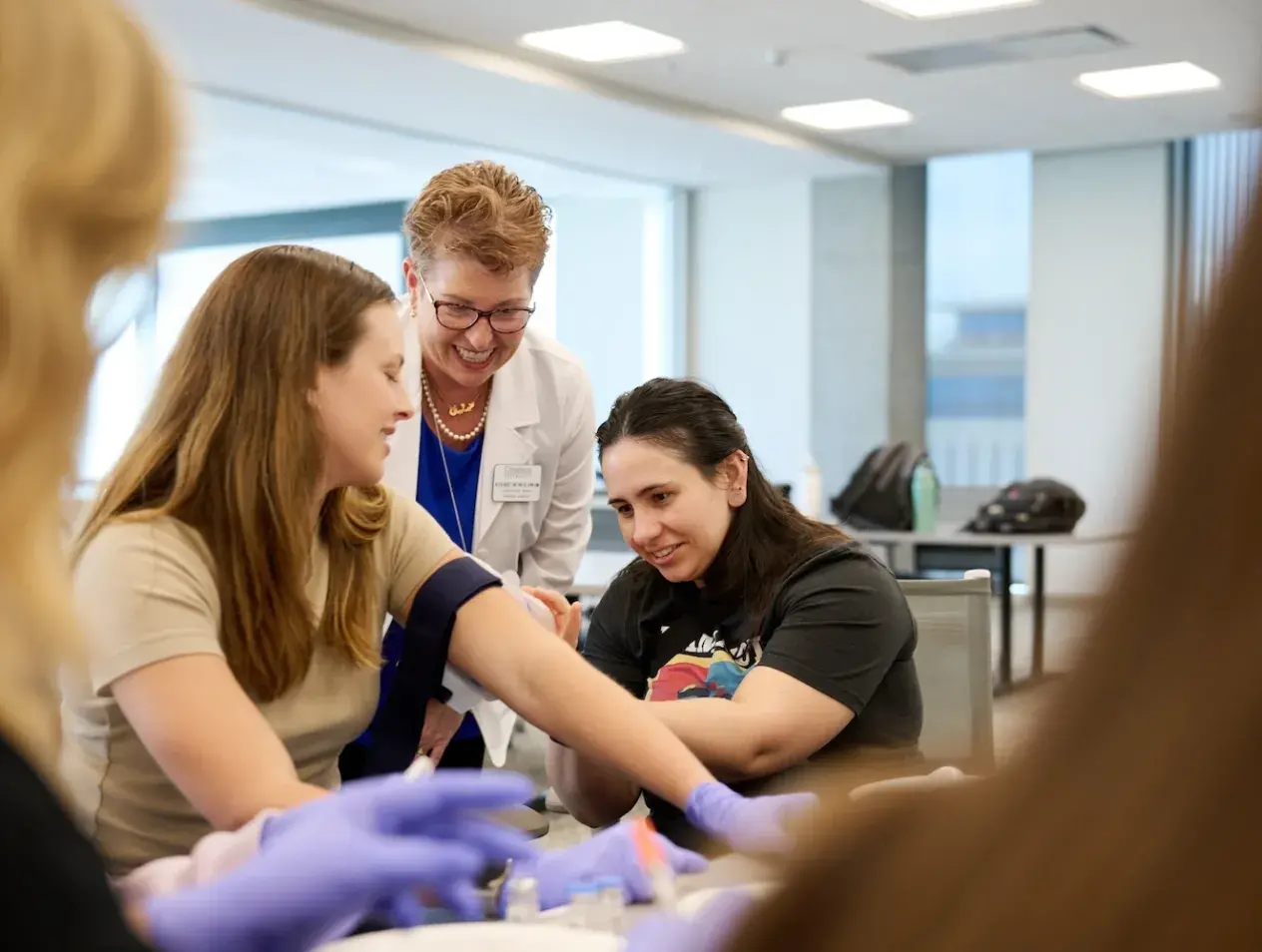 Nursing faculty member guiding student administering a shot.