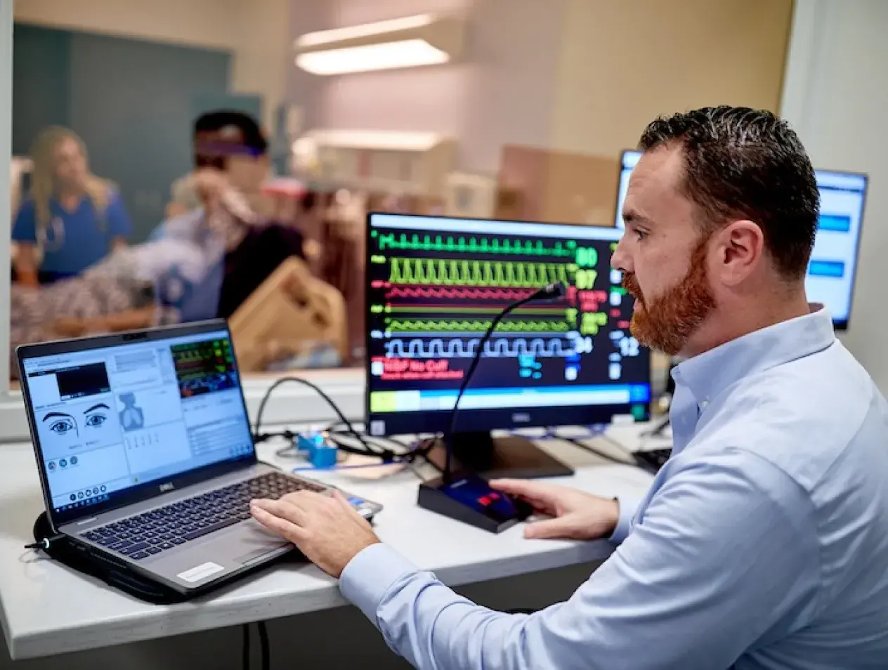Faculty member speaking into microphone guiding students in simulation lab.