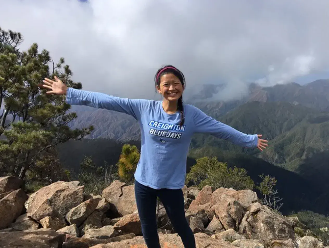Student standing with arms extended in exotic location.