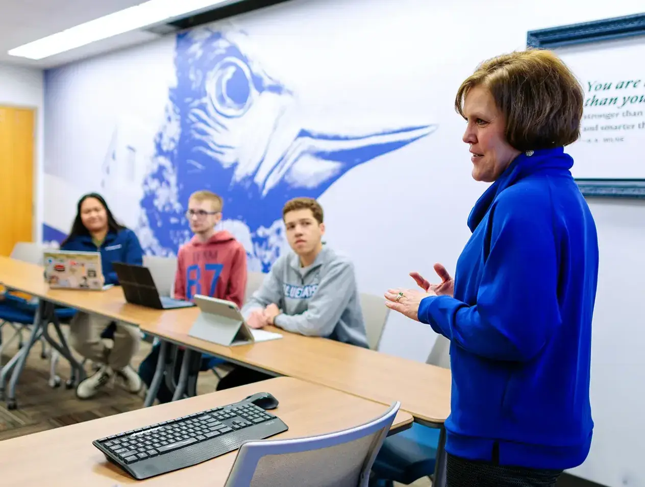 Woman instructing students in small classroom.