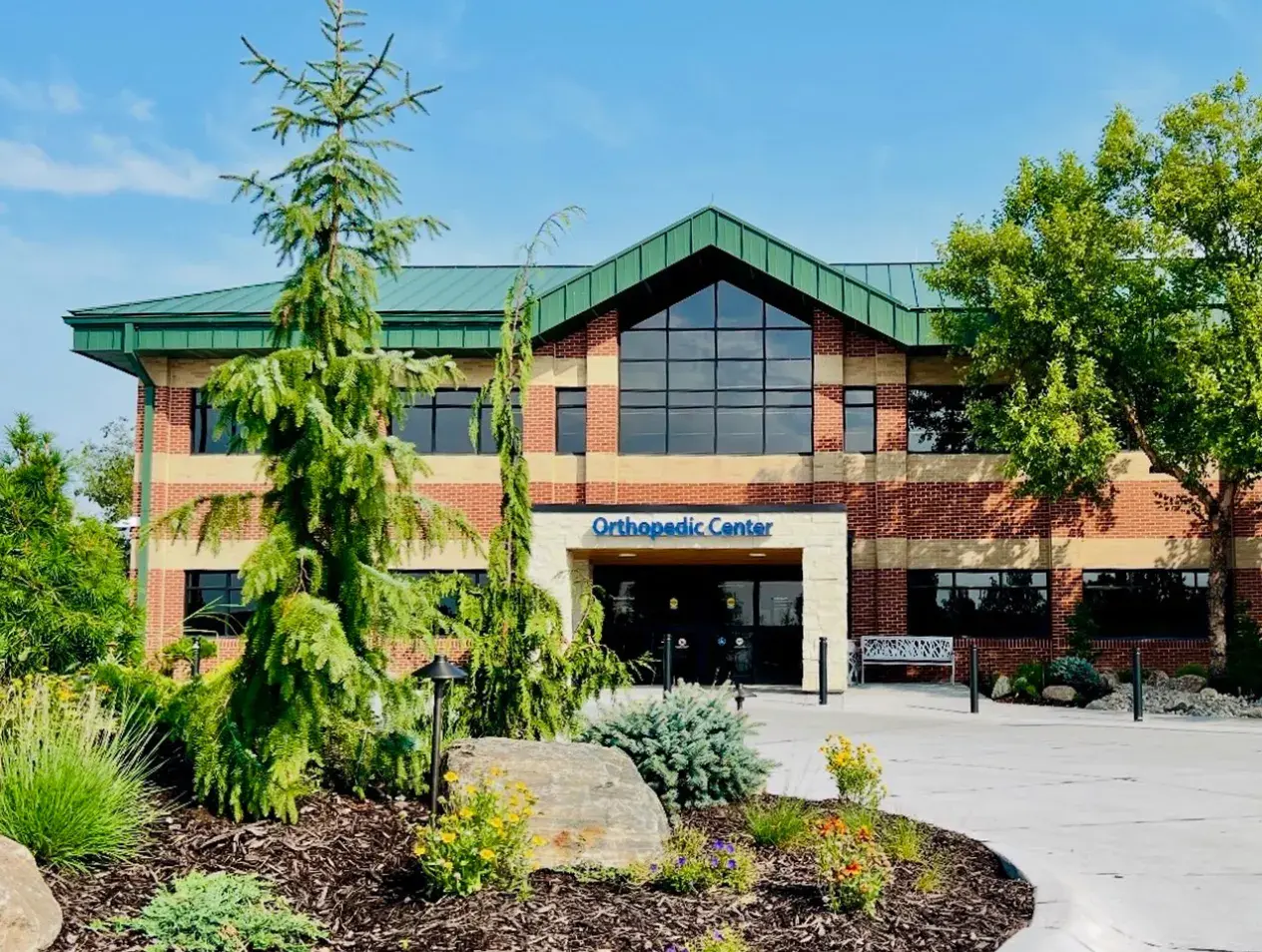 The Creighton Orthopedic Center building, a modern two-story facility with brick exterior, green roof, and landscaped entrance.