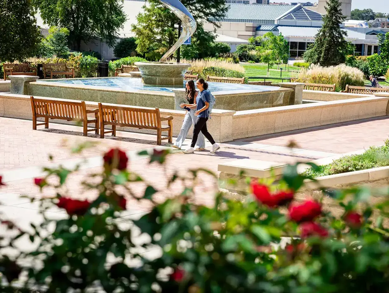 Students walking by fountain on summer day.