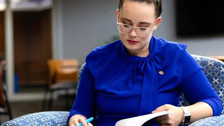 Woman studying from text book in lounge area.