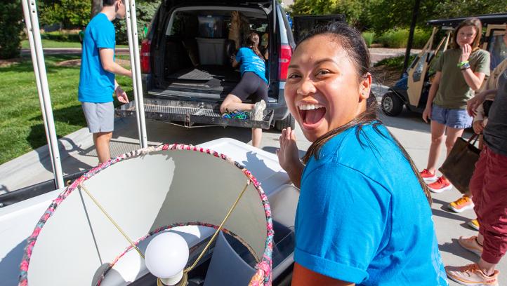 Creighton student smiles for camera while moving a lamp. 