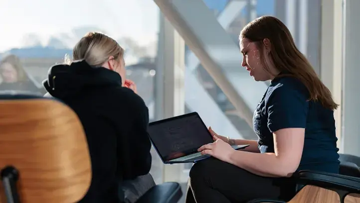 Two women talking while sitting in chairs in front of window