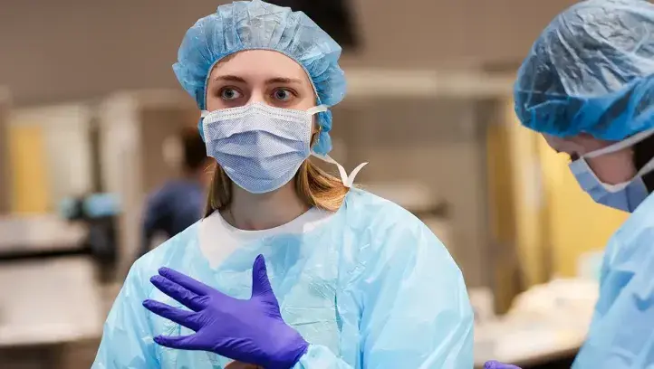 Health care professionals in standard cap, gown and gloves.