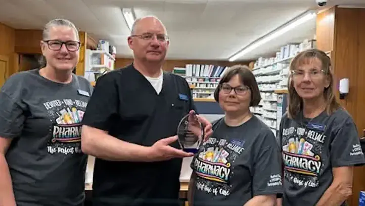 Pharmacists stand together holding award