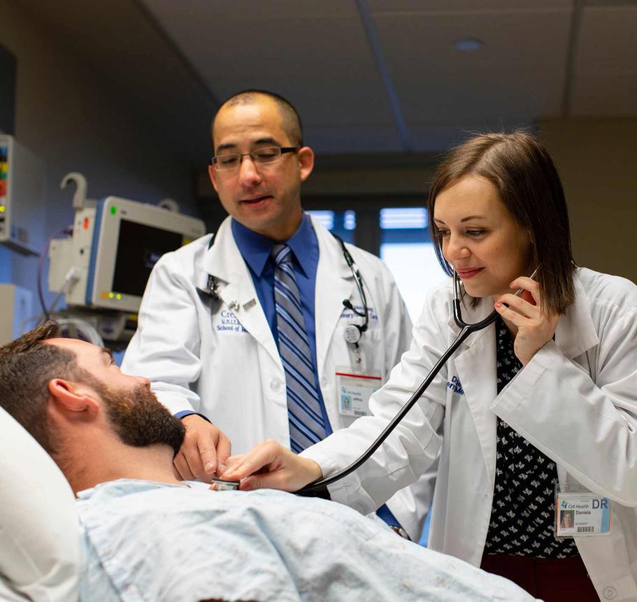 Faculty guiding a med student in examining a patient