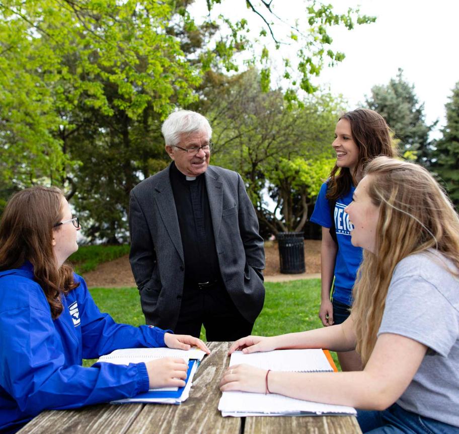 Jesuit faculty teaching students in outdoor setting