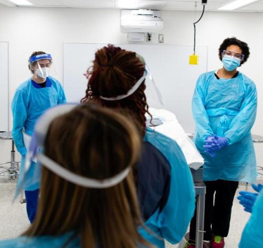 A group of medical professionals in PPE standing in a classroom