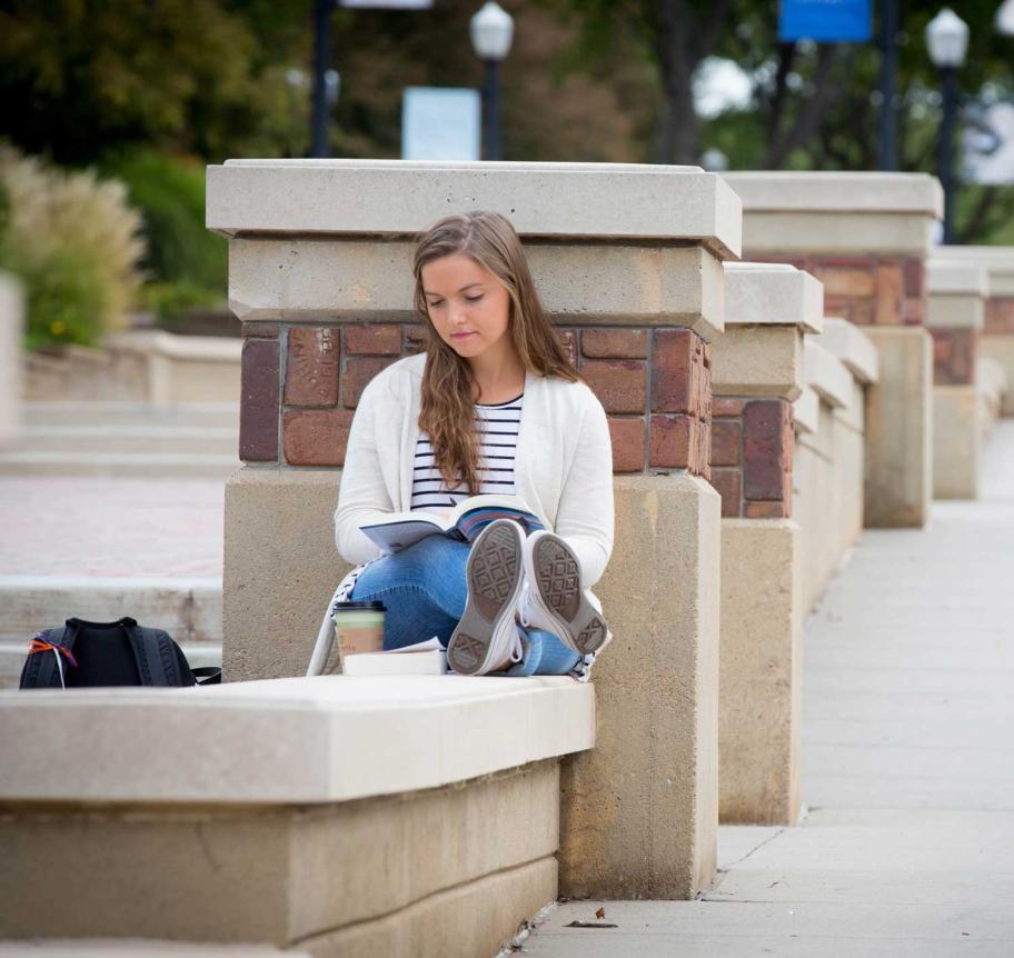 Student reading outdoors on Creighton campus Thumbnail