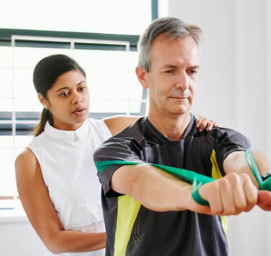A female physical therapist helps a man through resistance band exercises Thumbnail