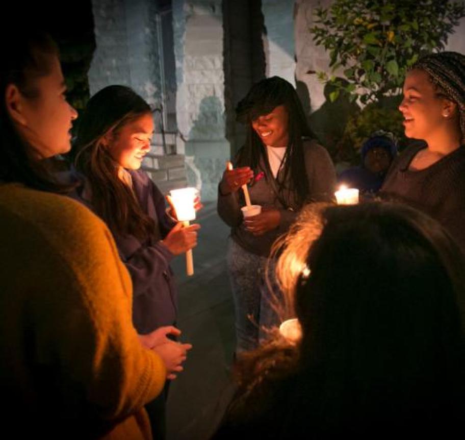 Students in a circle holding candles at night Thumbnail