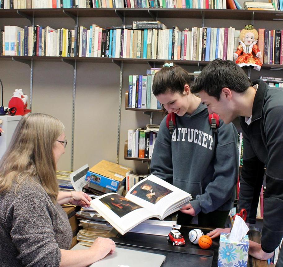 Students looking at art book in classroom
