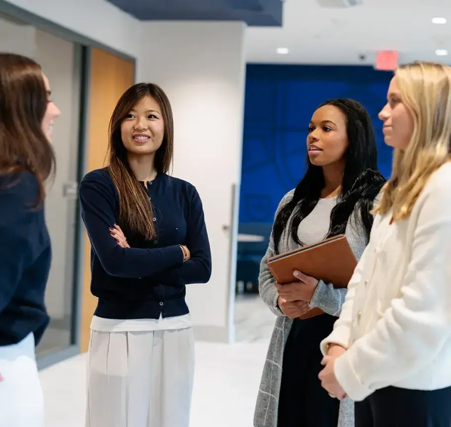Young professionals in business attire engage in conversation in a contemporary office space with blue accent walls.