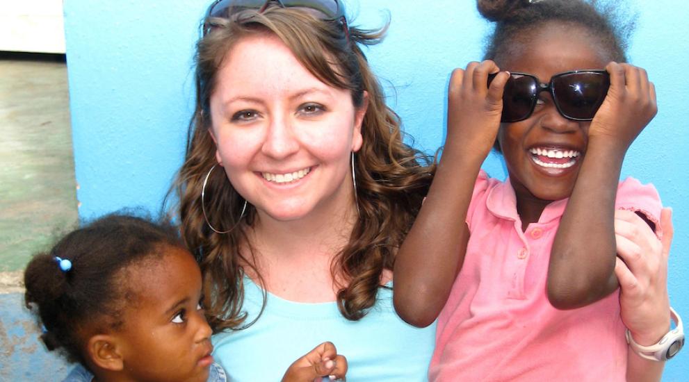Female Creighton student with Dominican children smiling and having fun.