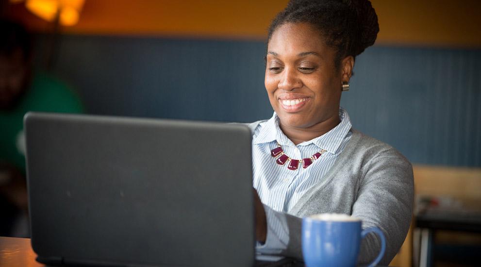 A woman smiling while using a laptop