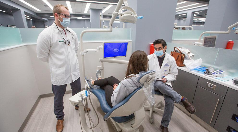 Dental students consulting with a patient in an exam room