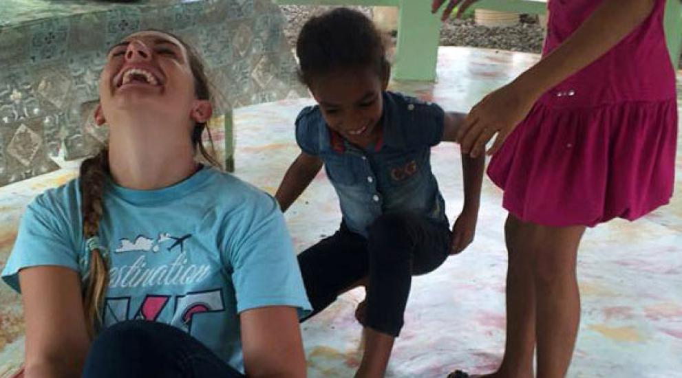 A Creighton student playing with children while on a service trip in the Dominican Republic