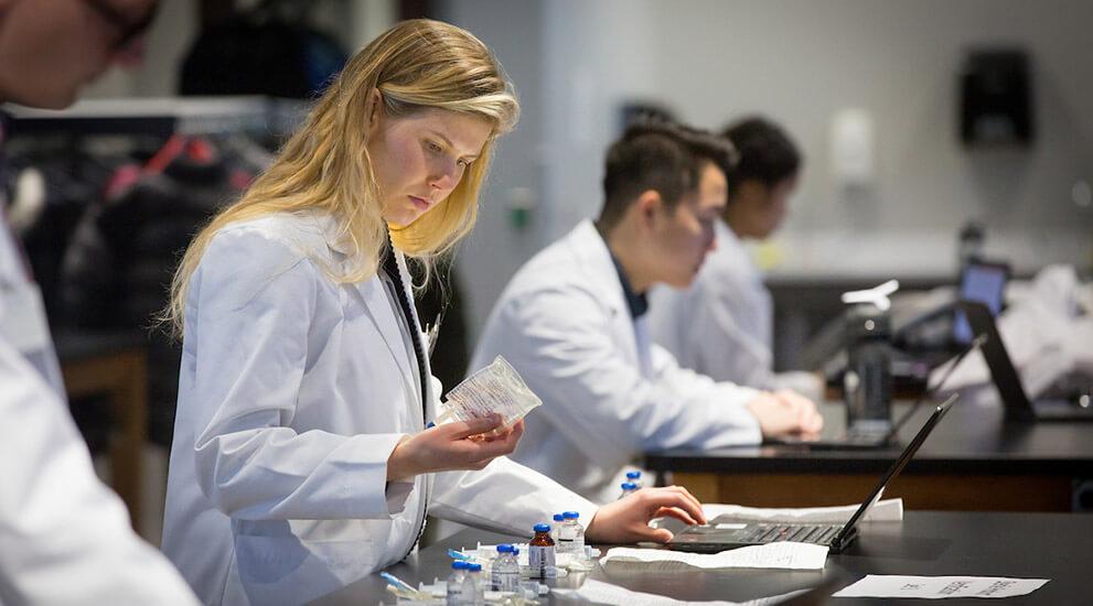 Pharmacy students assessing medication during a lab exercise