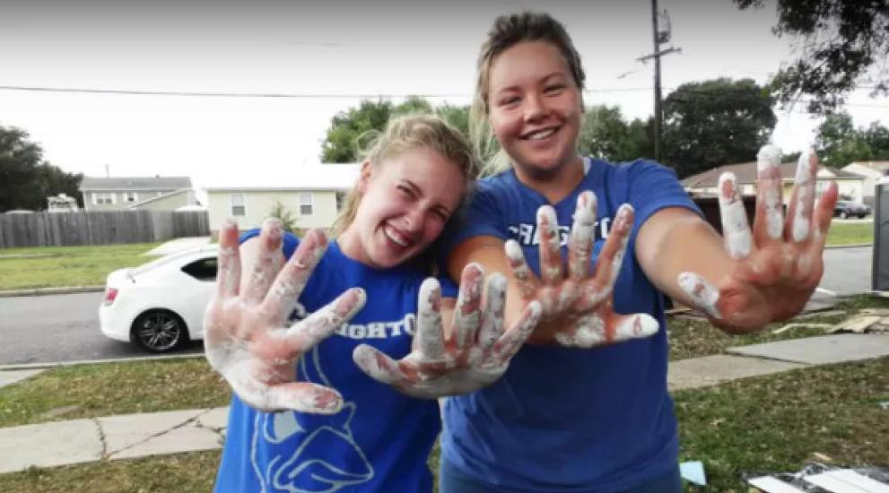 Video thumbnail featuring Creighton students with paint on their hands during a service trip