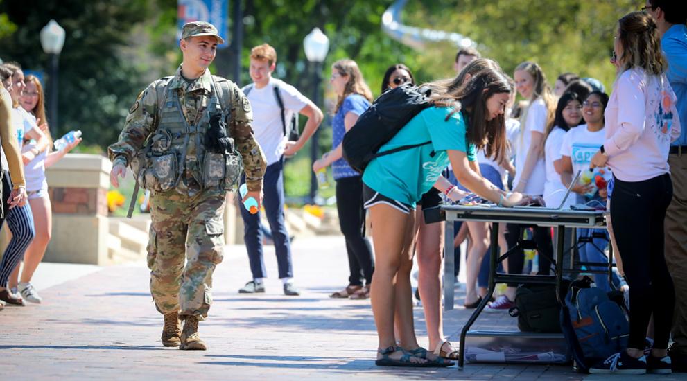 Service person walking on Creighton campus among civilians.