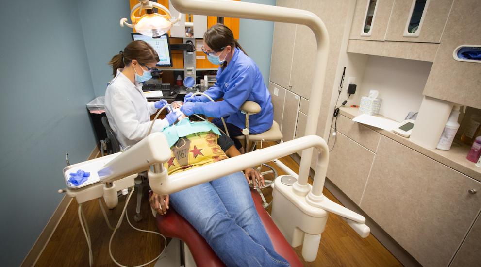 Dental student shadowing dentist during patient procedure.