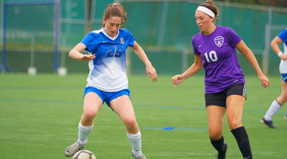 Two women club soccer players competing.